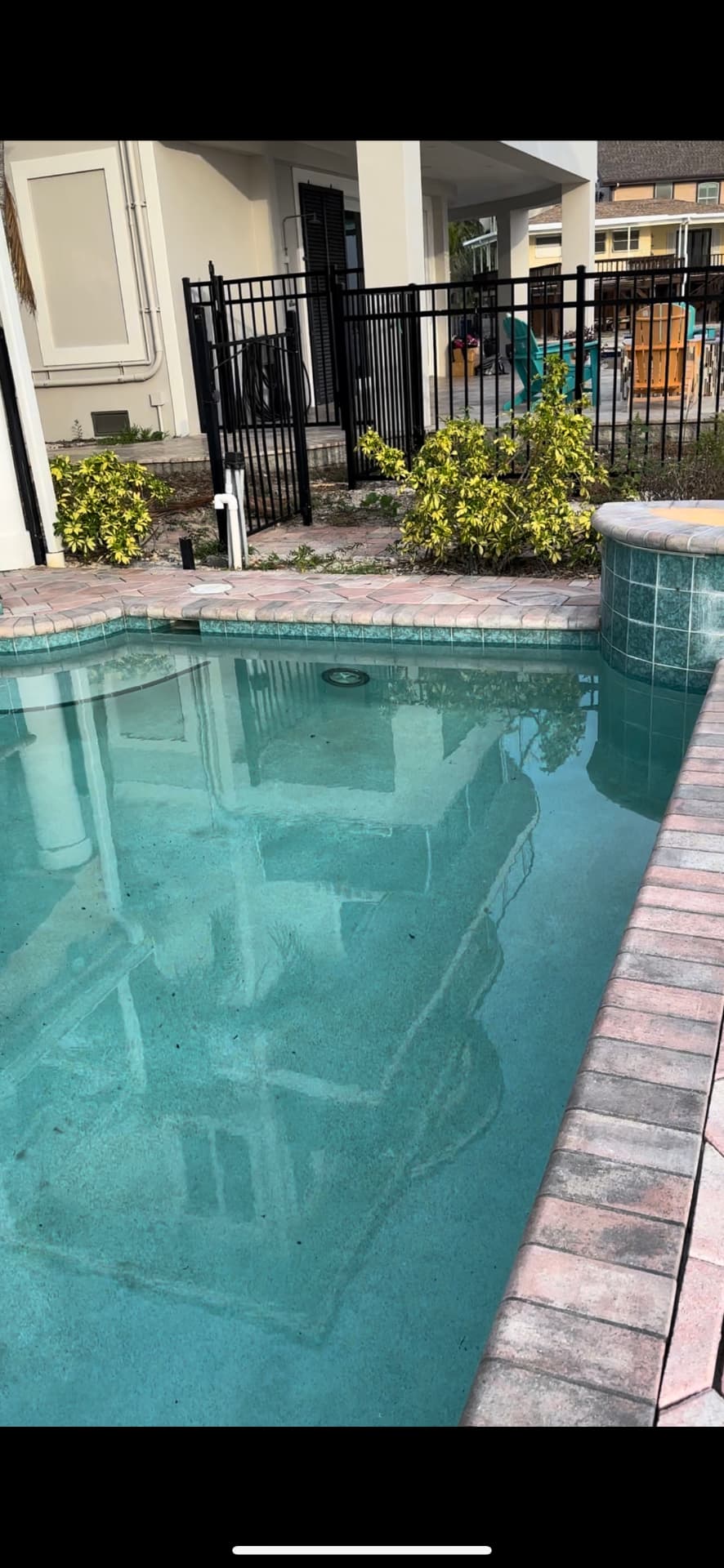 Worn, mottled pool interior with aged plaster and dated green tile before restoration