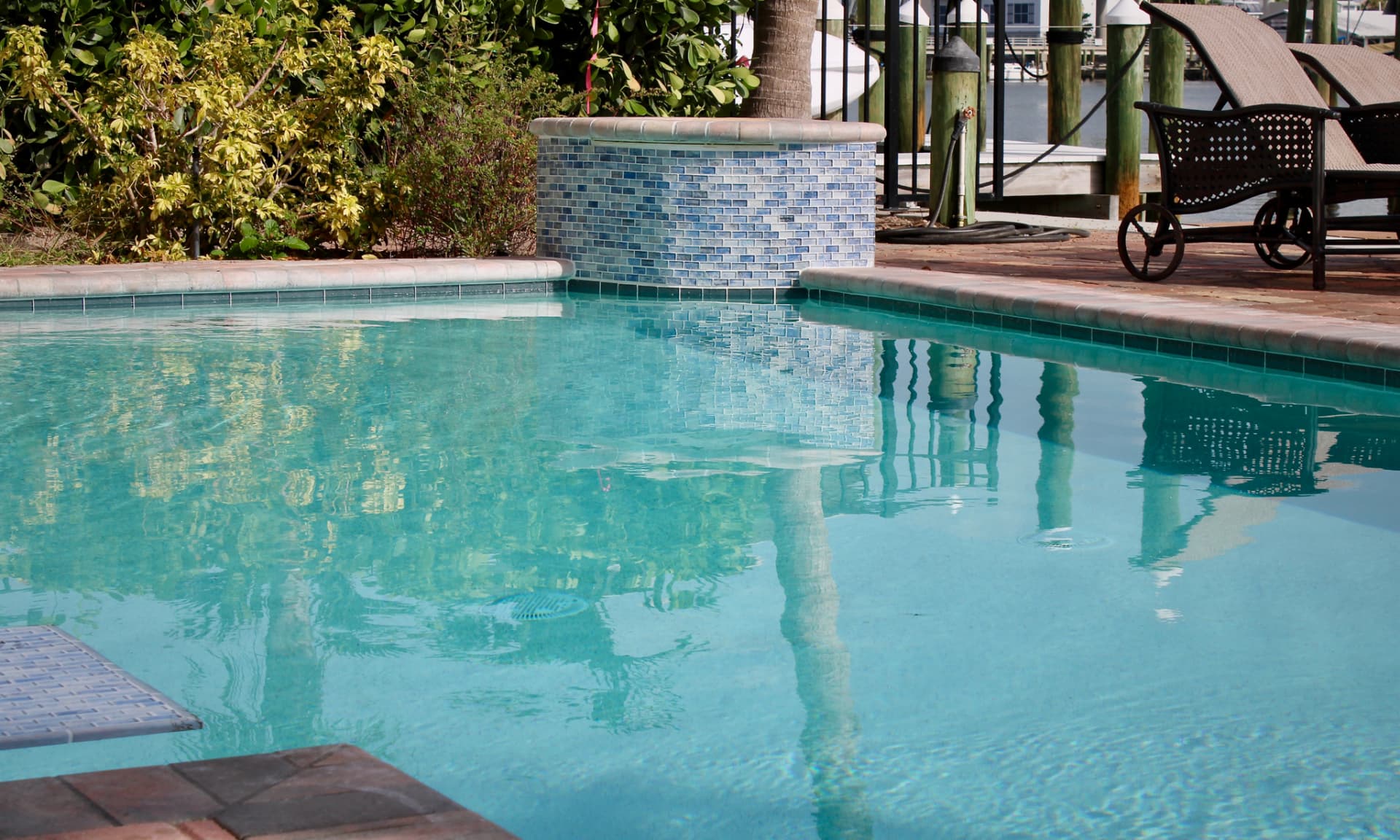 Pool with a blue glass mosaic tiled spa and brick paver deck