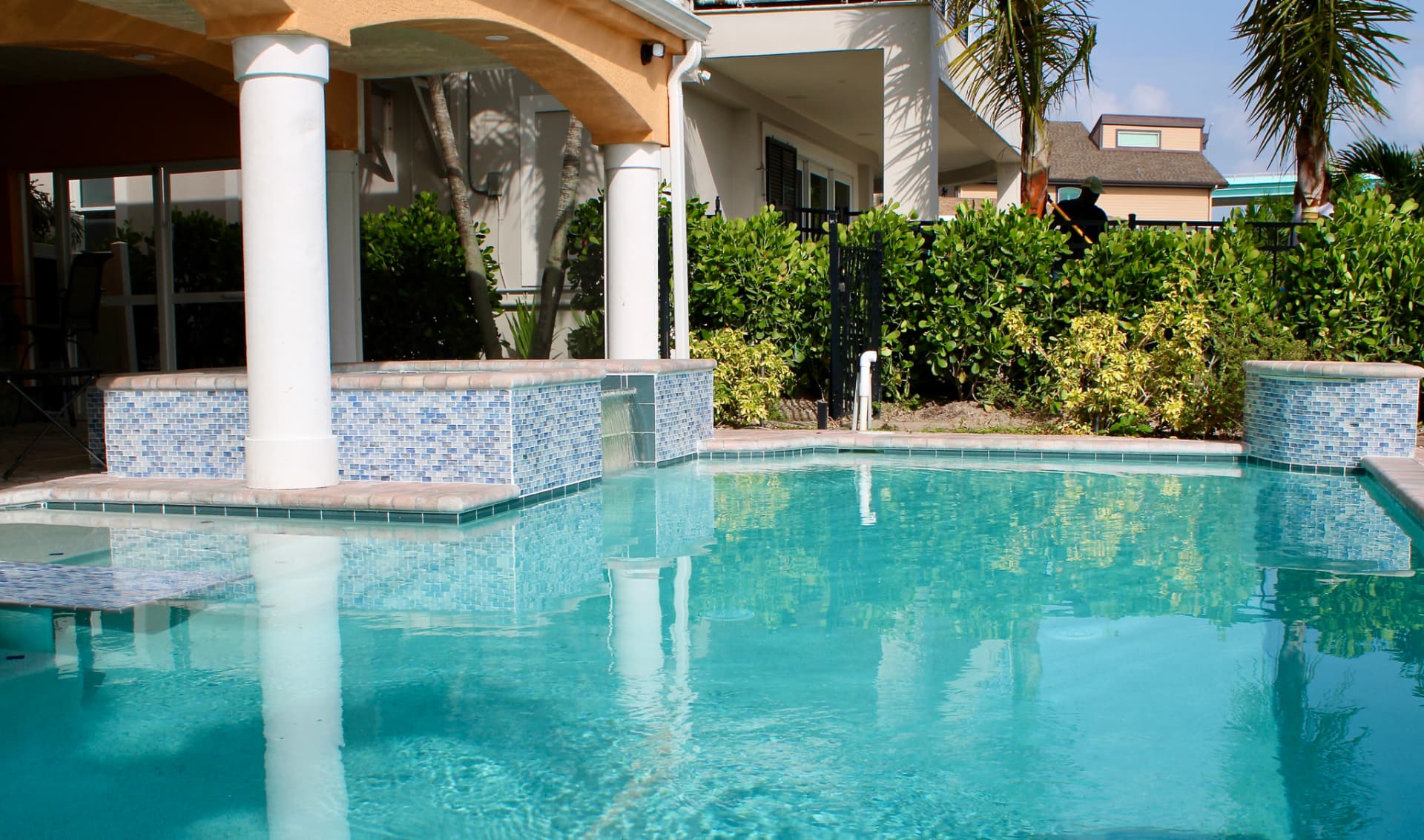 Pool with a raised blue glass tile wall and sheer descent waterfall