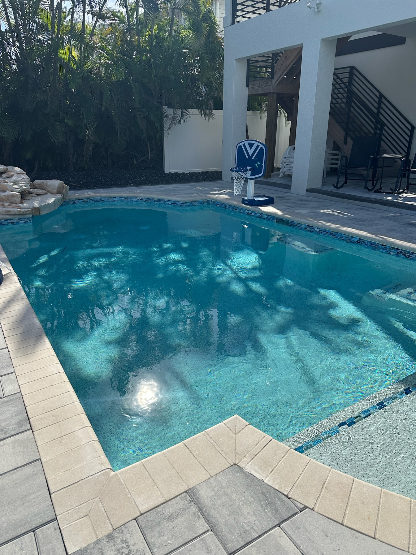 Backyard pool with a natural rock waterfall feature and iridescent glass waterline tile