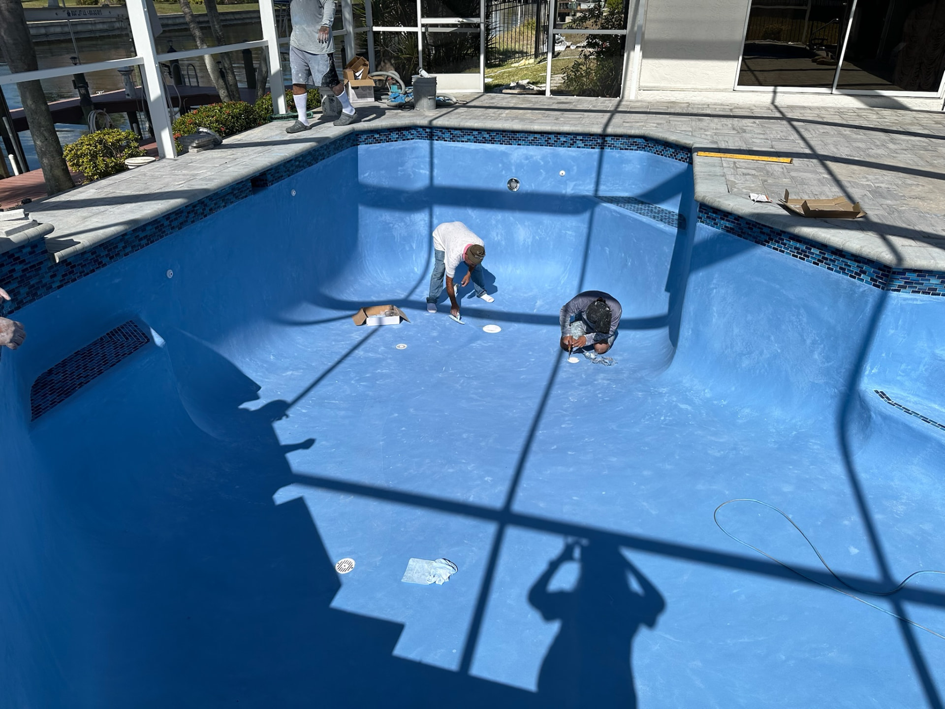 Eden crew hand-troweling a new blue plaster interior finish in a drained pool